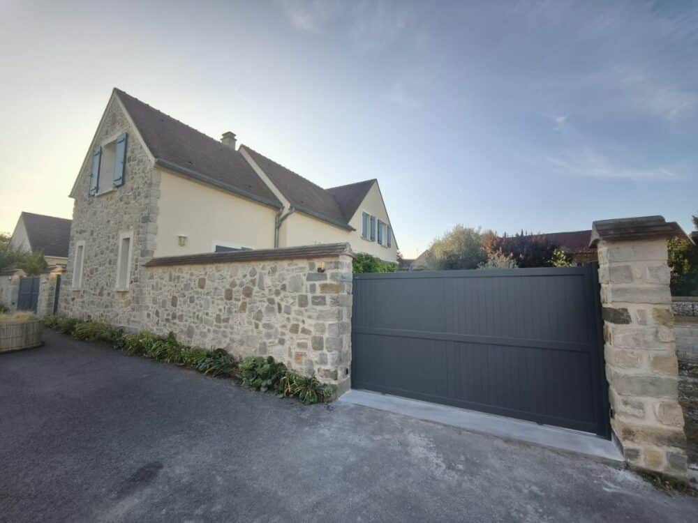 Portail coulissant Kostum Menez gris installé devant une maison à Ury